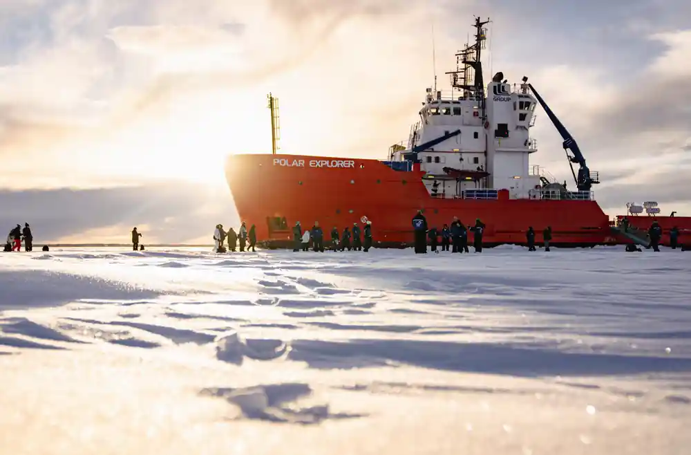 The bow of the icebreaker over the ice with passengers standing beneath