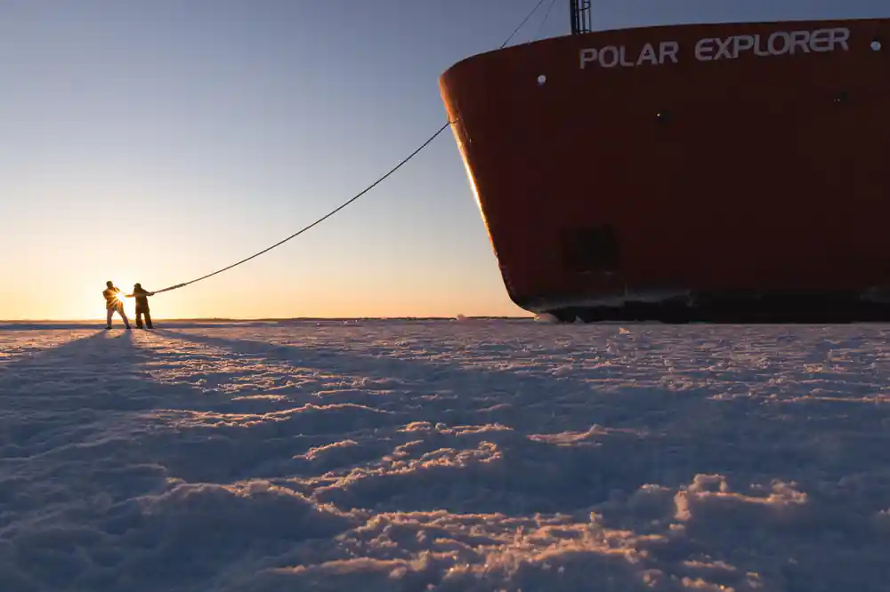 The bow of the icebreaker at sunset with the hull name lit