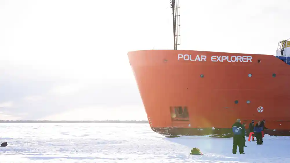 The bow of the ship with its name painted on the hull, low over the ice