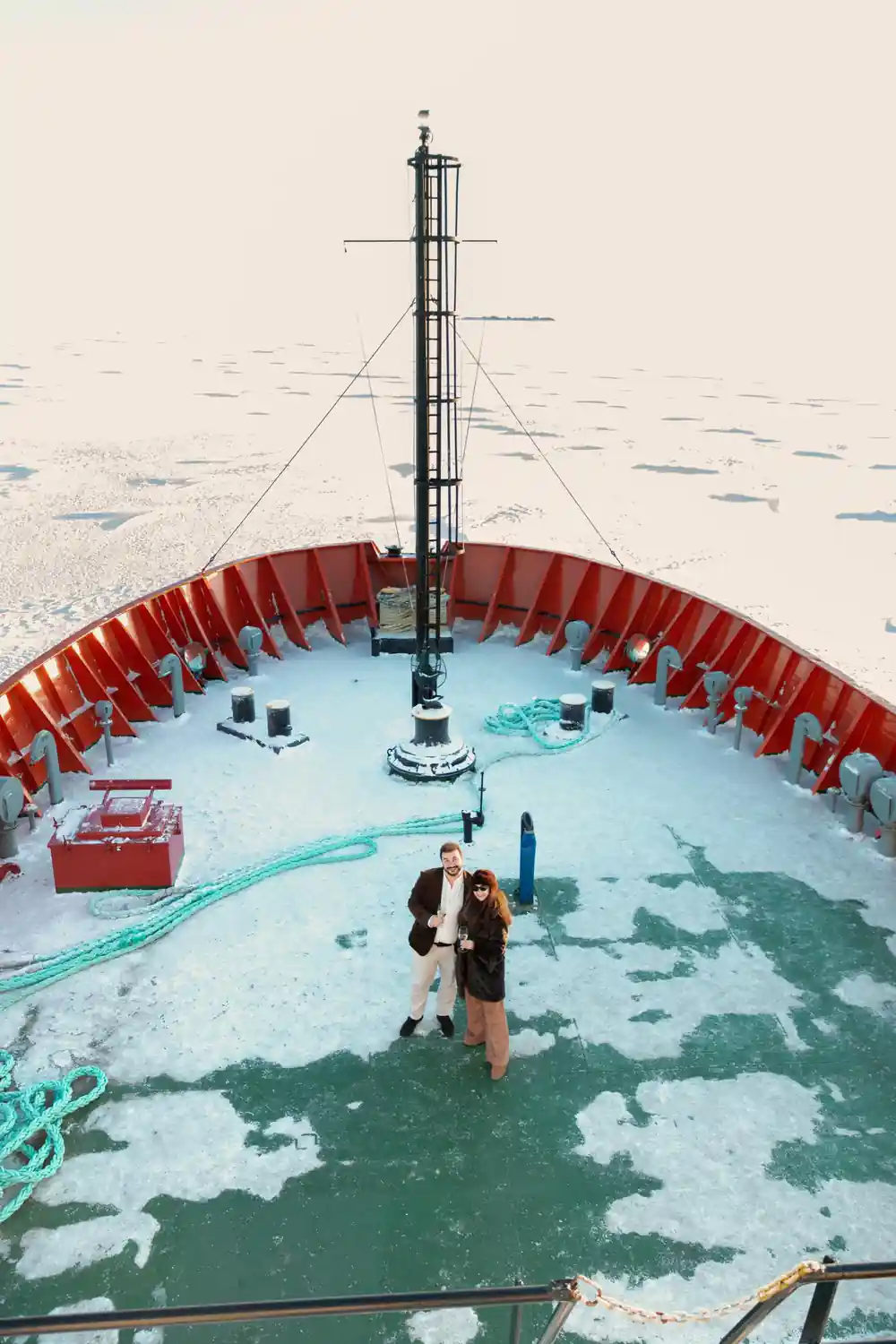 The foredeck from above, with two passengers standing on the ice below the bow