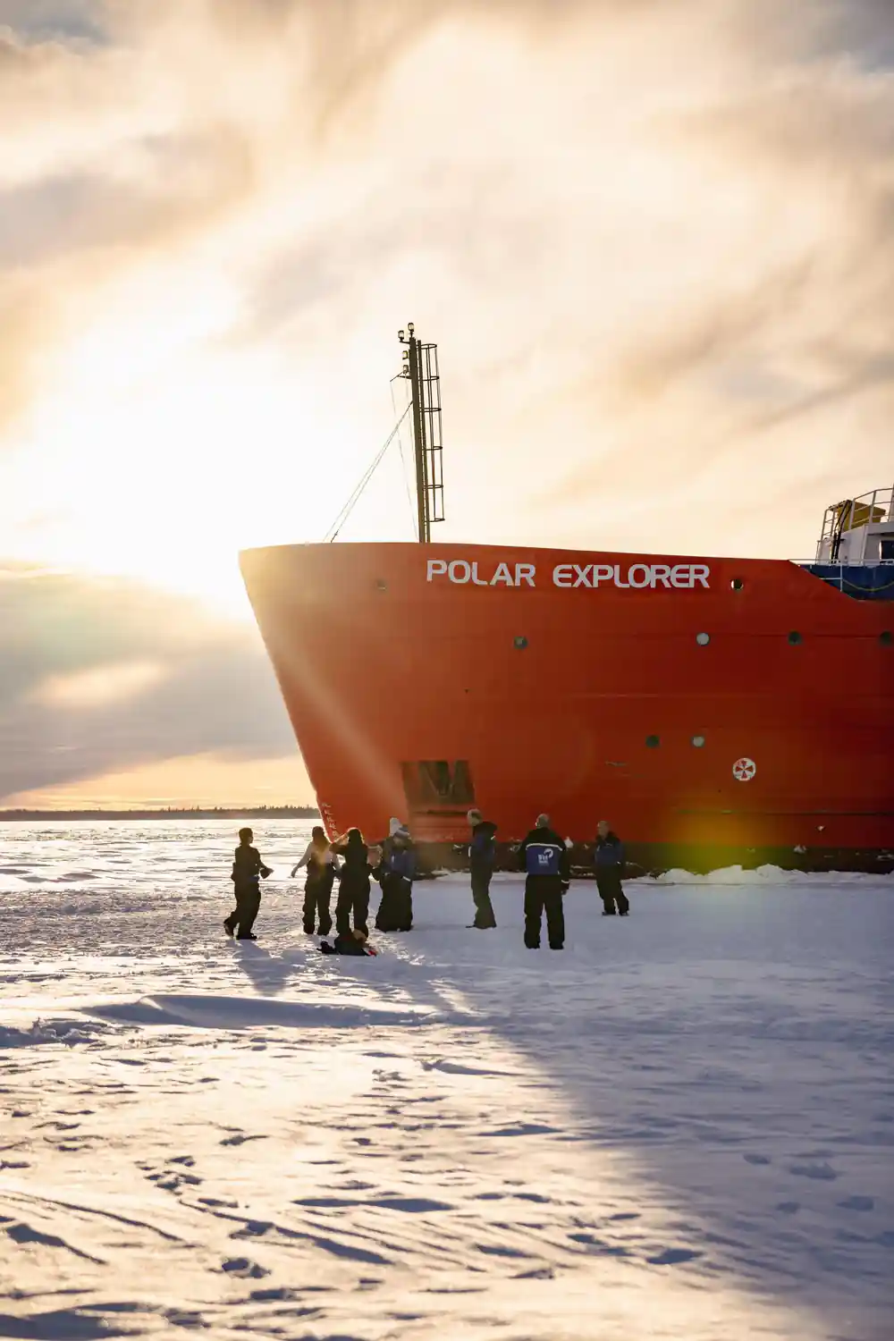 A group standing under the bow, the ship name lit from behind