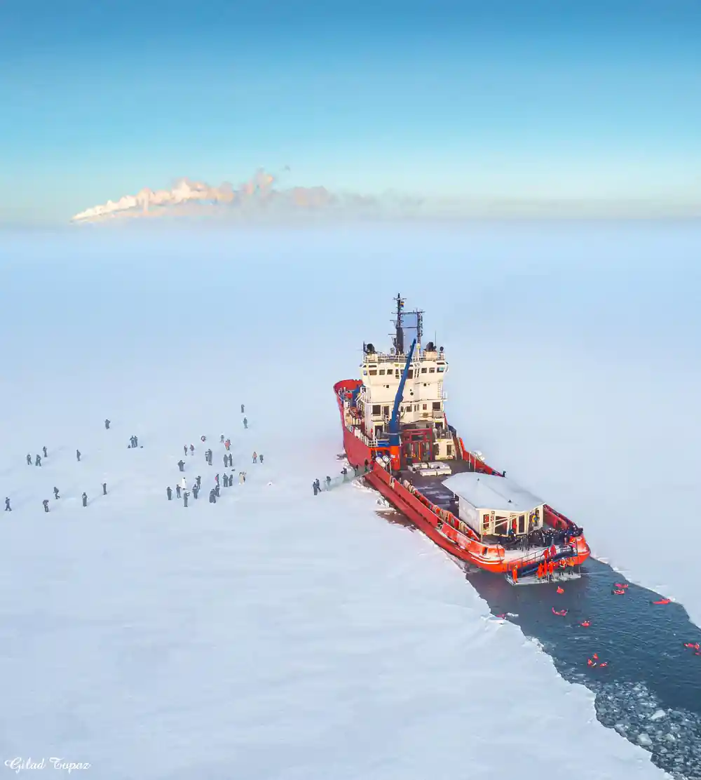 The icebreaker on the horizon with a long line of people walking out to it