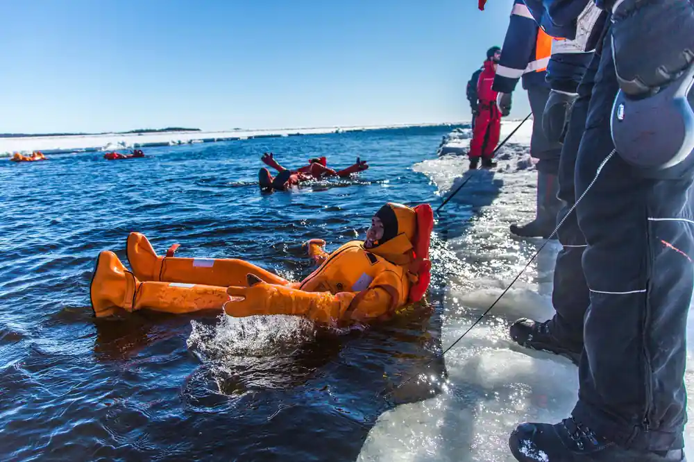 A passenger floating in the channel with others watching from the ice edge