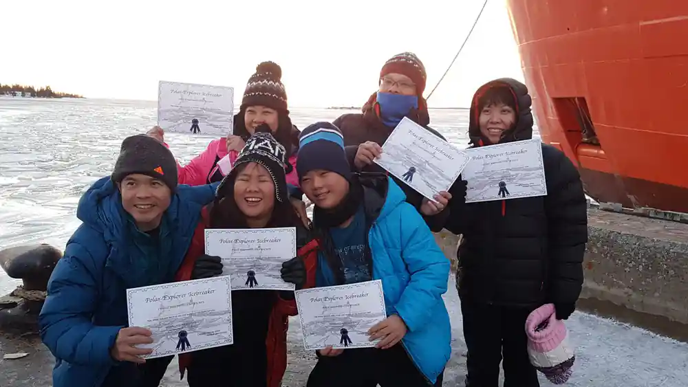 Passengers holding up their cruise and swim certificates on deck