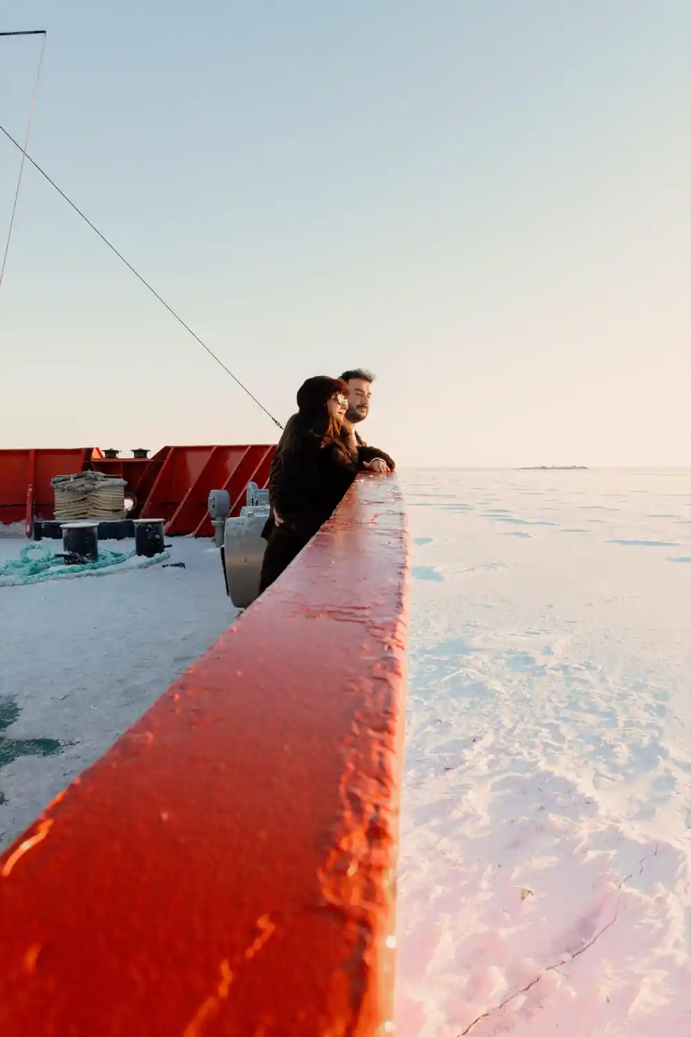 Passengers leaning over the bow rail looking down at the ice