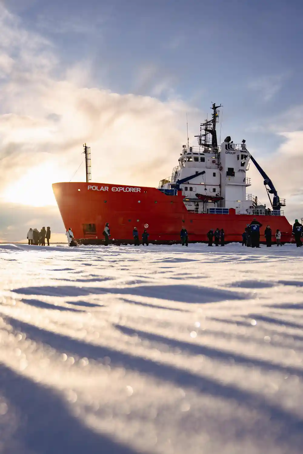 The red hull broadside on the ice with a line of passengers along it