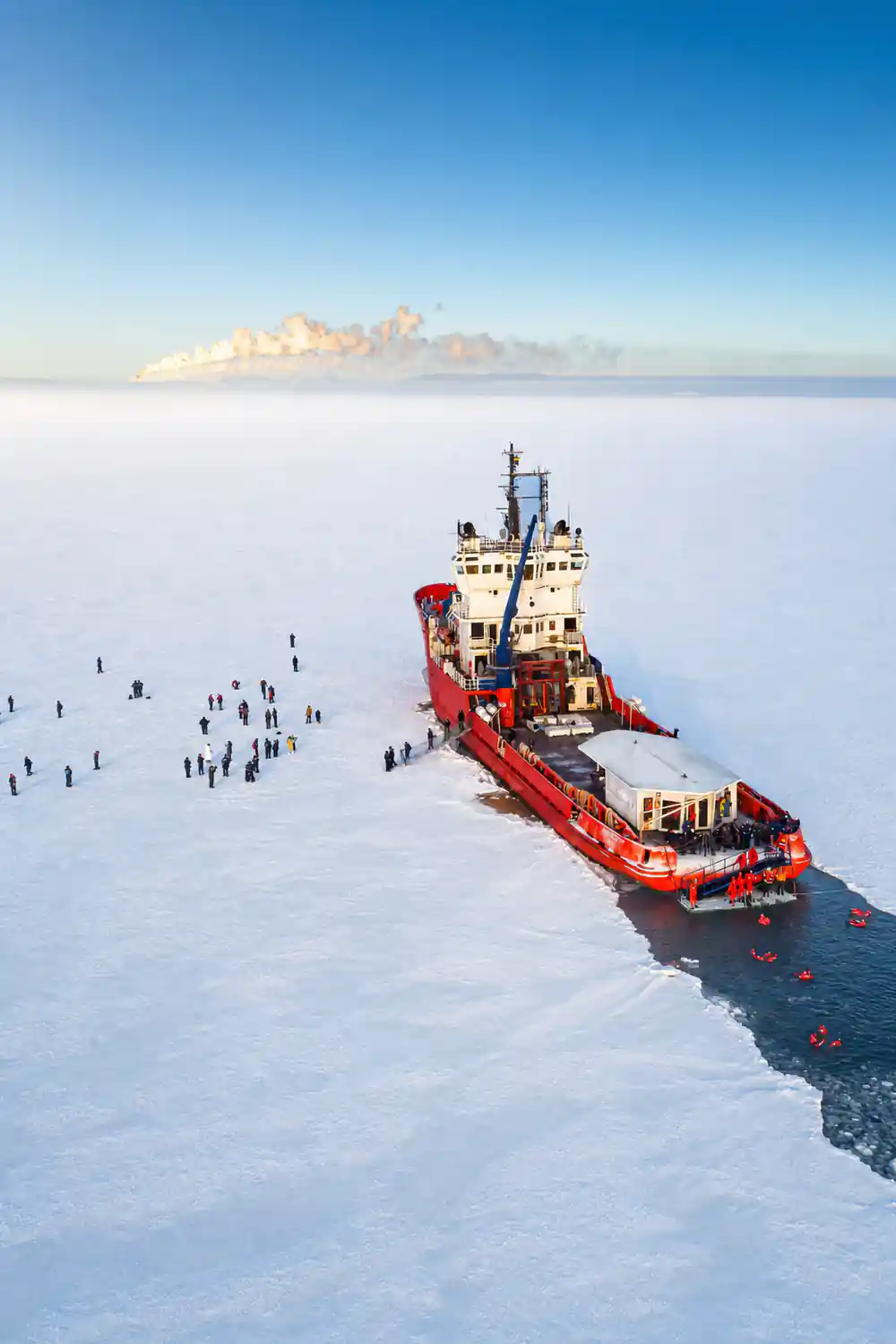The ship stopped on the ice field with passengers spread out across it