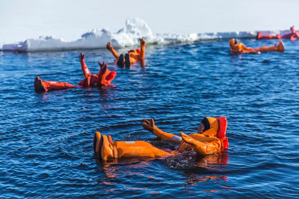 Two passengers floating on their backs in open water among ice